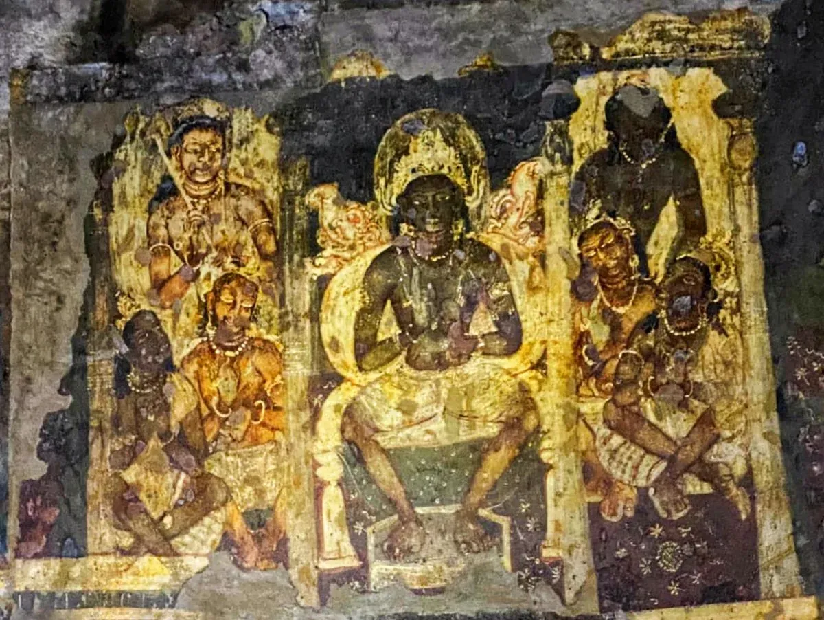 अजंता की गुफा की दीवार पर बना रंगीन चित्र: बीच में बैठी एक आकृति और आसपास सेवक