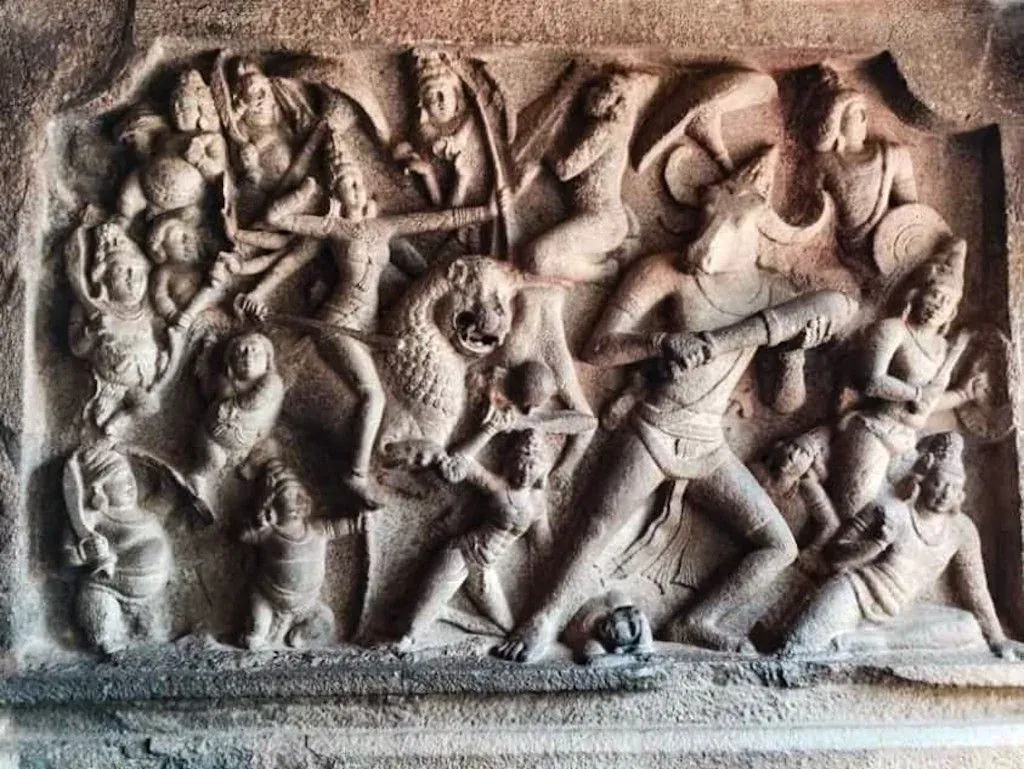 चट्टान में उकेरा दृश्य: शेर पर सवार कई भुजाओं वाली दुर्गा और सामने भैंसे के सिर वाला असुर