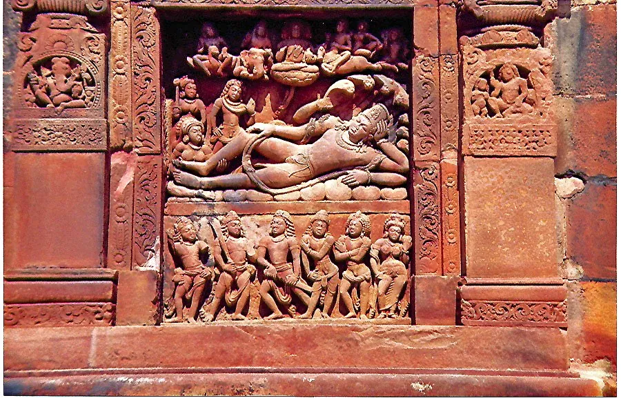 पत्थर की पट्टी पर उकेरी मूर्ति: शेषनाग पर लेटे विष्णु और आसपास आकृतियाँ